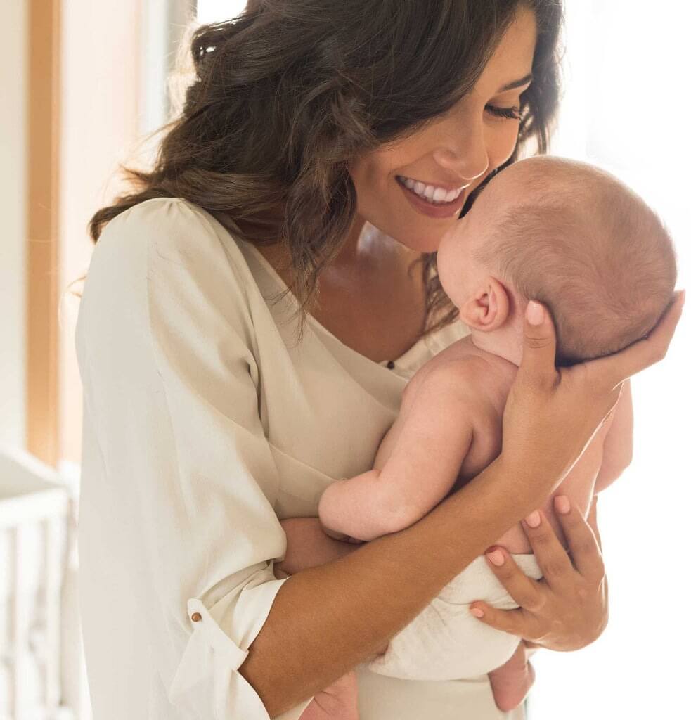 mom smiling and holding infant close to her face